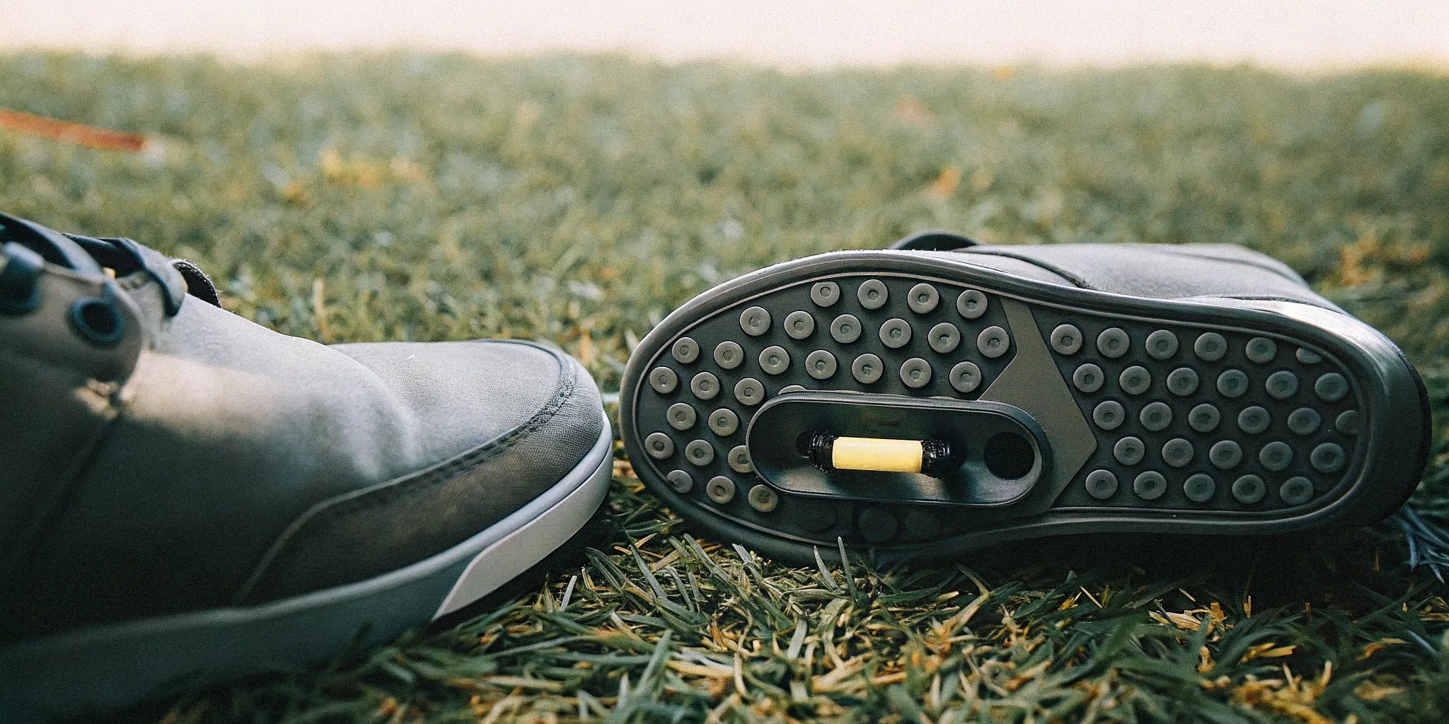 Premium grounding shoes placed on green grass showing conductive sole element.