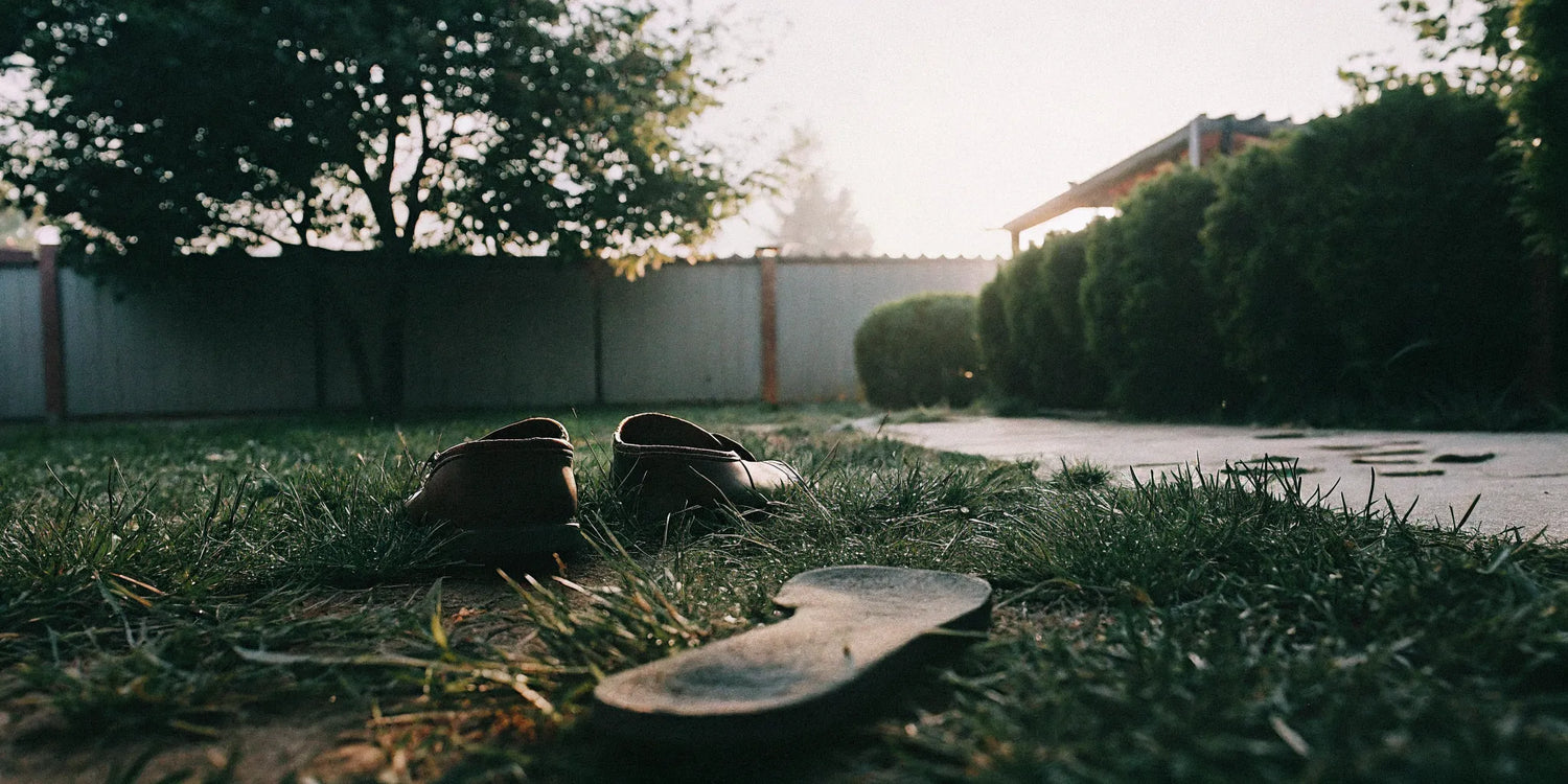 Grounding shoes beside a barefoot footprint on grass