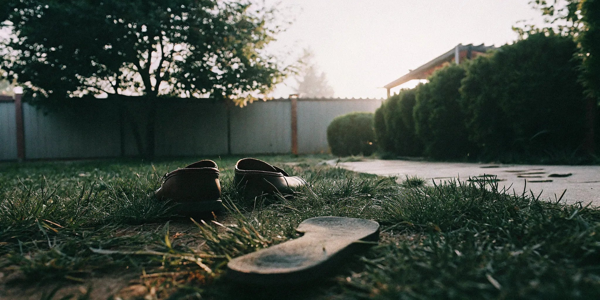 Grounding shoes beside a barefoot footprint on grass