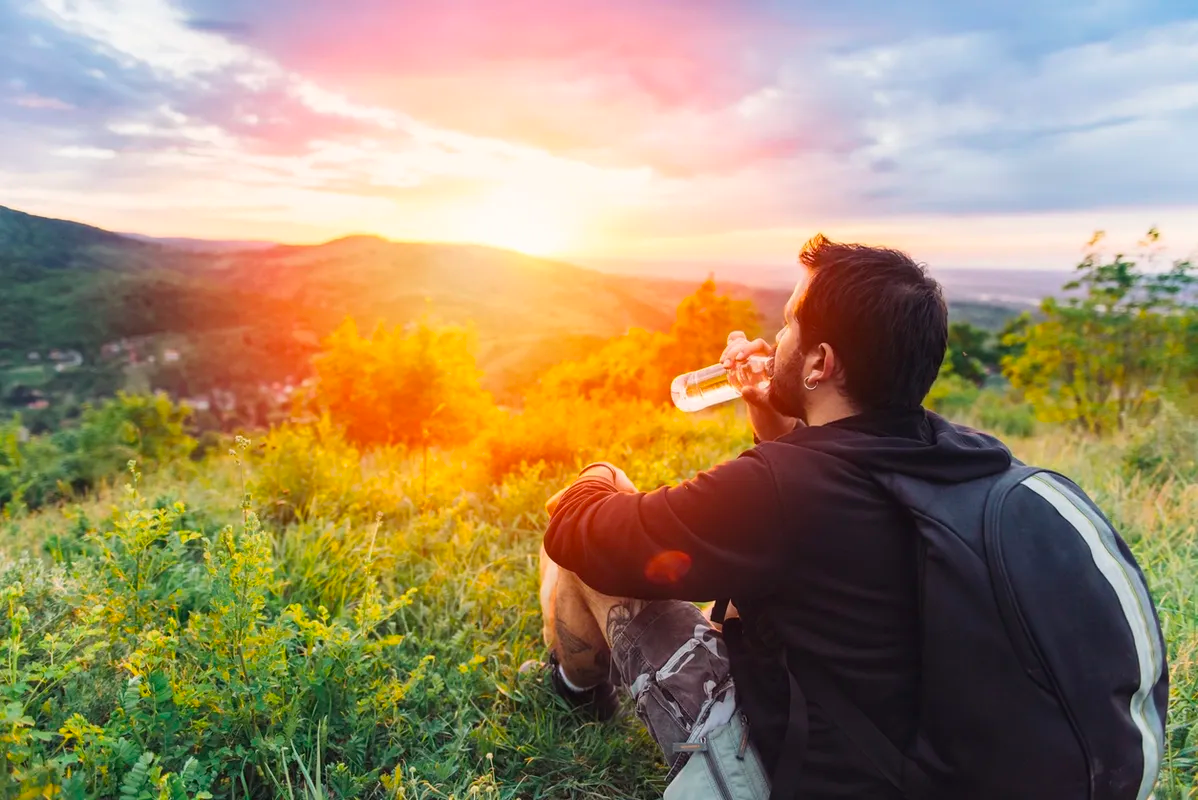 Man sitting in the mountains looking at the sunset