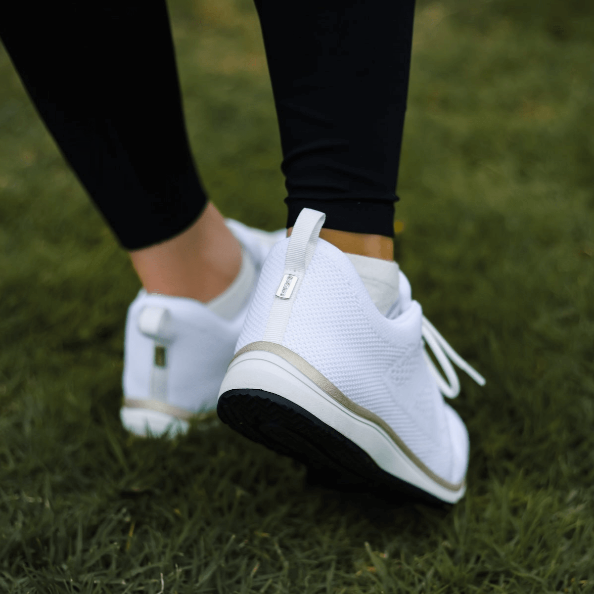 Behind view of Harmony 783 White and Gold grounding knit lace-up for women on grass