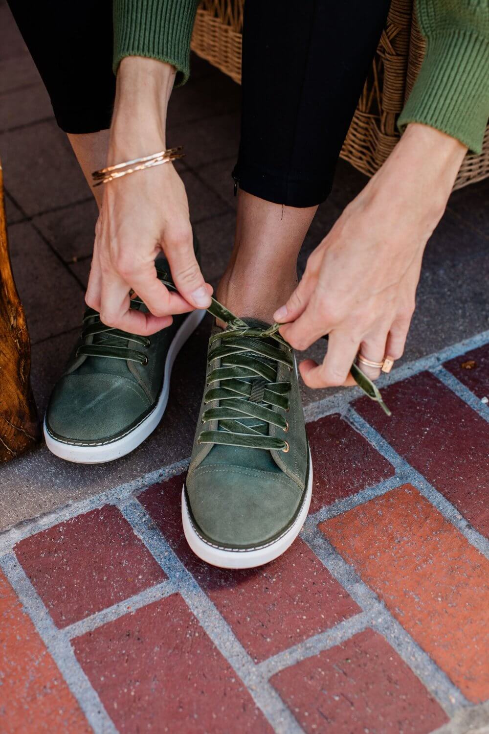 Woman tying shoelaces on olive green grounding suede walker