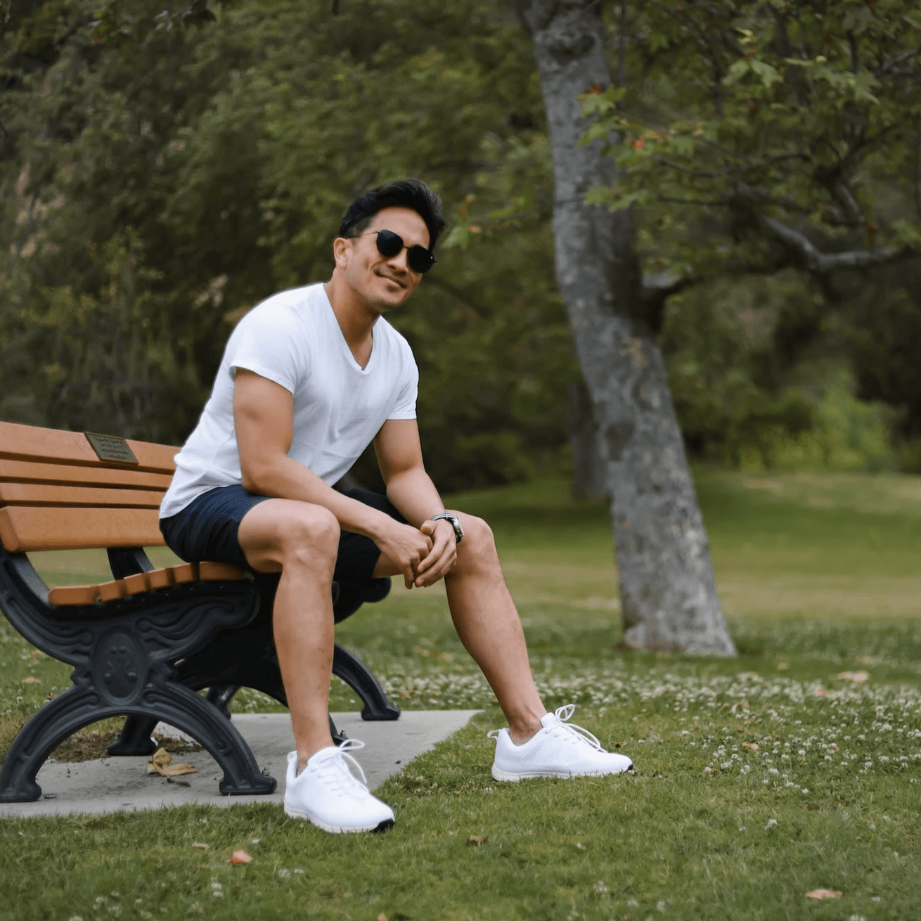 Man wearing white recycled plastic lace-up tennis shoes for grounding in park