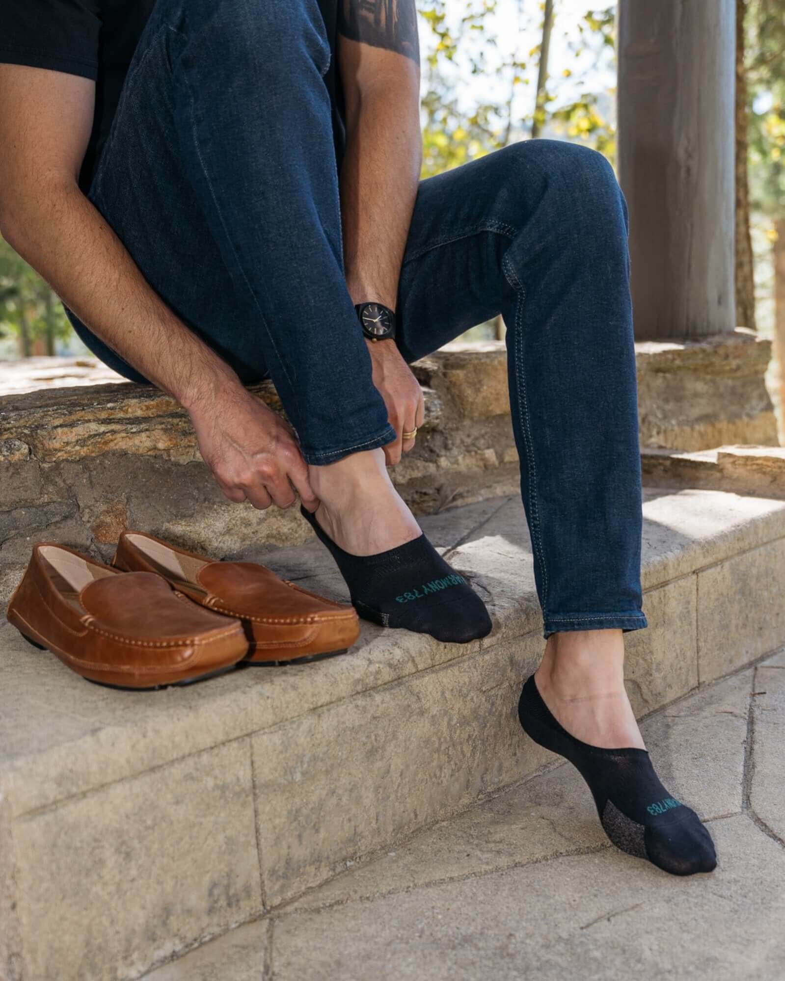 Close up of man sitting on Stone stairs wearing Harmony 783 No Show black Grounding earthing socks Organic Cotton