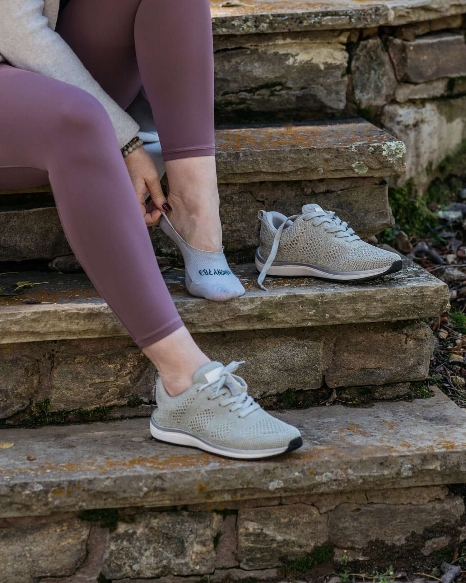 women sitting on stone steps wearing Harmony 783 No Show Grey Grounding earthing socks Organic Cotton putting her shoes and socks on
LIfestyle
