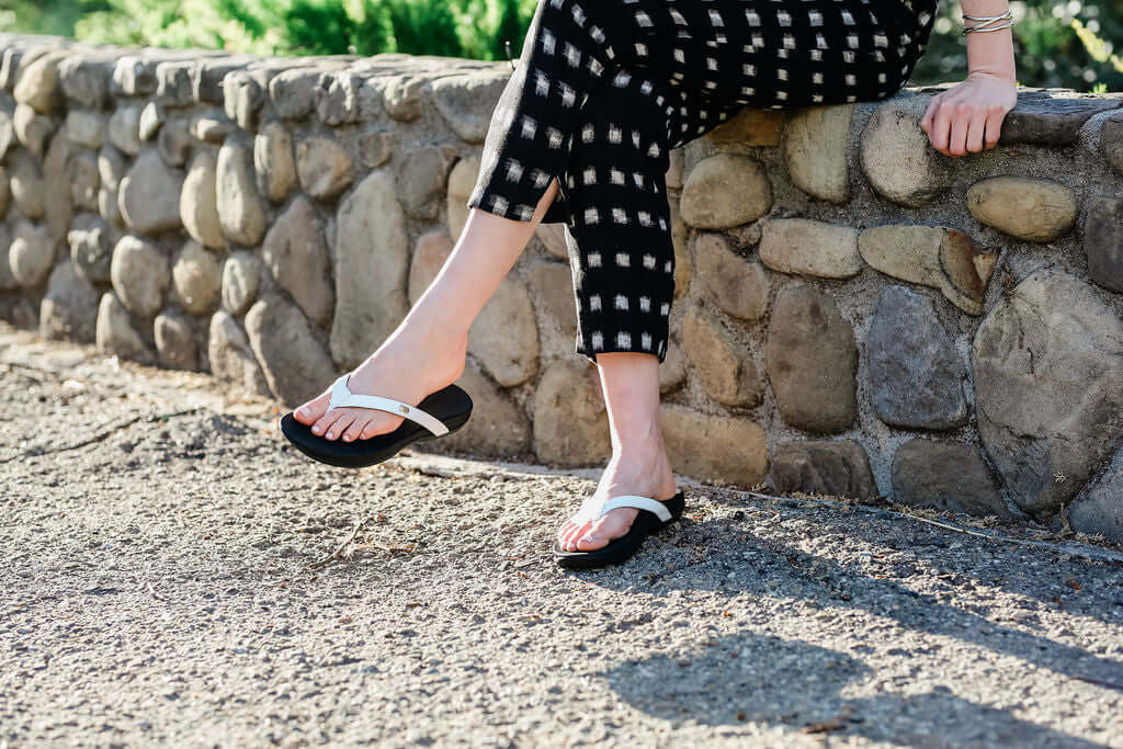 Woman sitting on stone with her feet on gravel wearing Harmony 783 Women’s Lily White leather Grounding Conductive Earthing Sandal Flip Flop
Lifestyle2