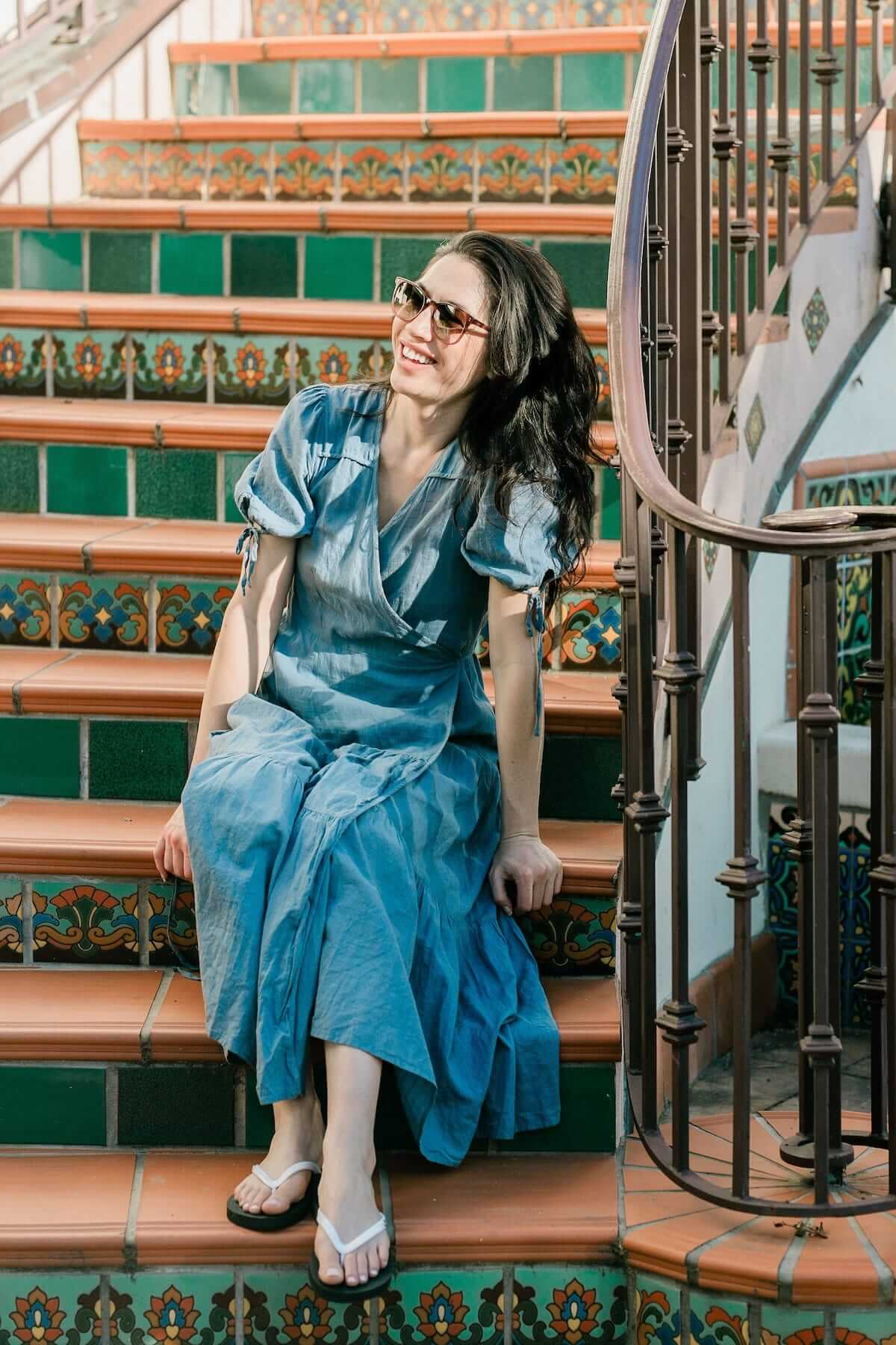 Woman in blue dress sitting on stairs or steps wearing black and white conductive plug flip flops