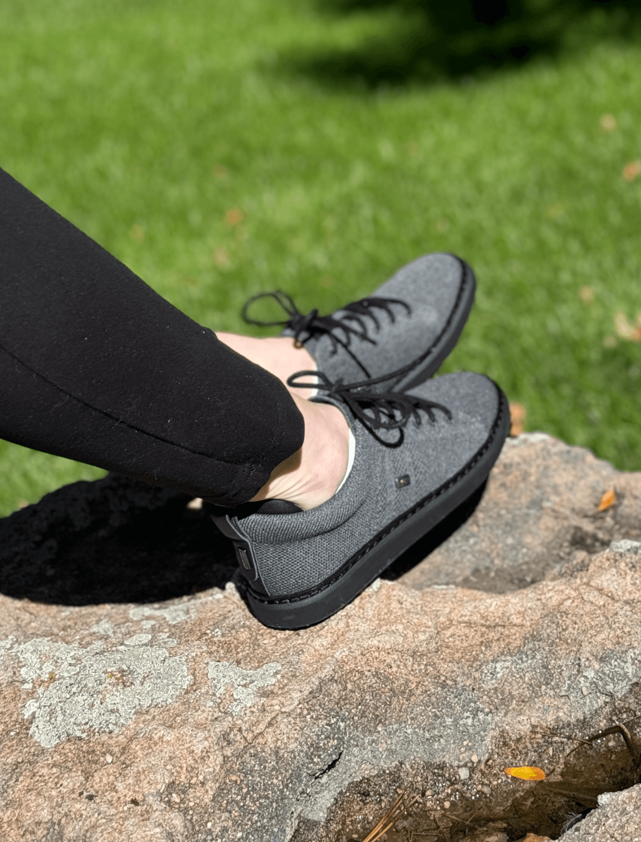 woman sitting on rock wearing black and charcoal grounding knit walkers