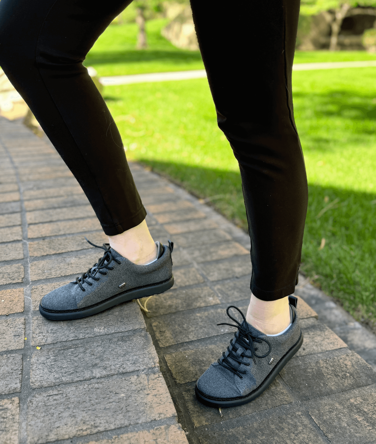 woman standing on brick steps wearing black and charcoal knit grounding walkers