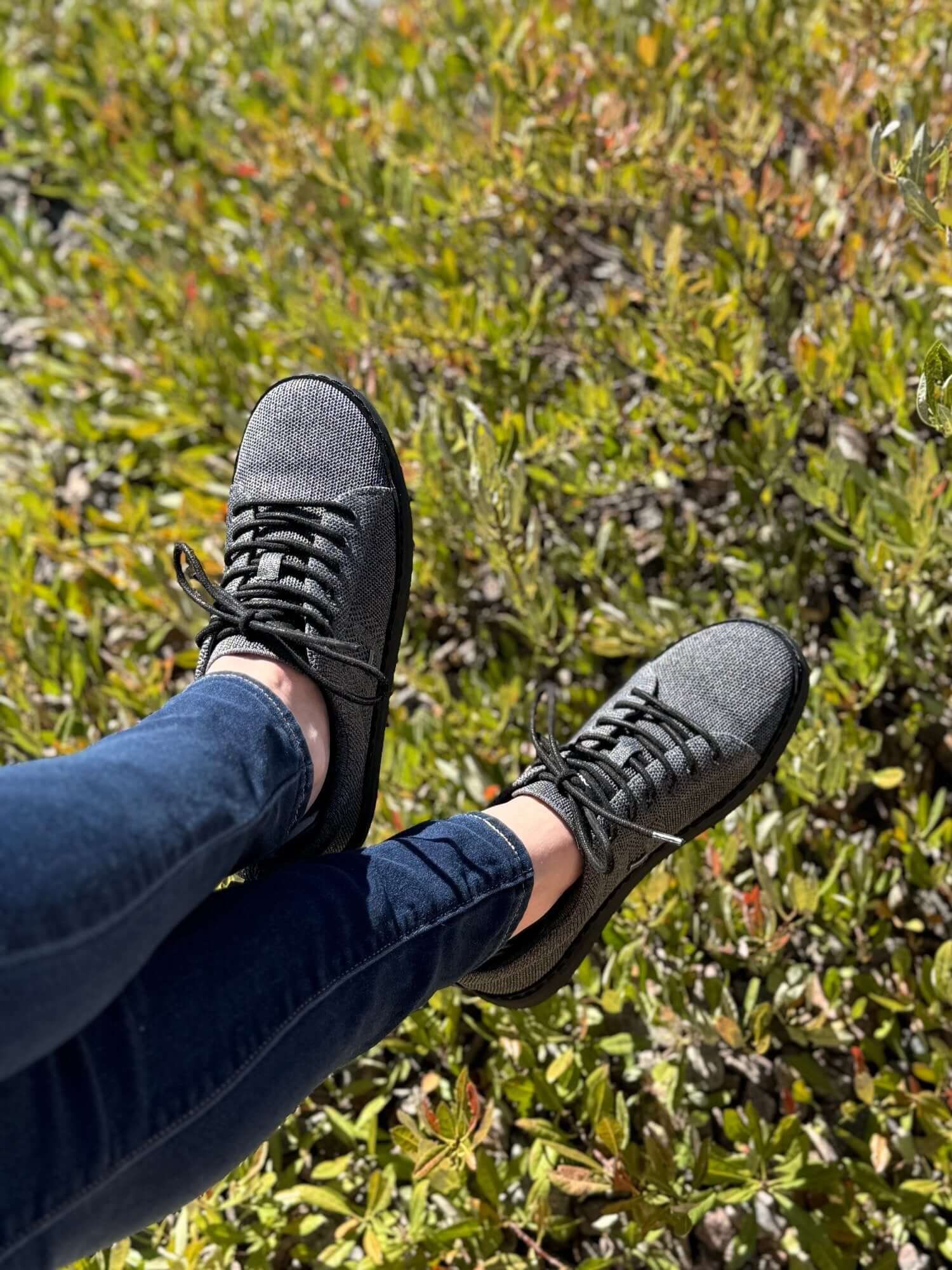 woman sitting with feet overlooking greenery wearing black and charcoal knit grounded walkers