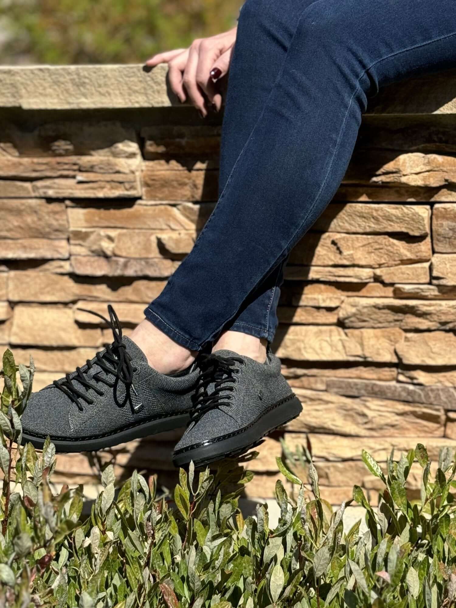 woman sitting on stone wall wearing black and charcoal grounding knit walkers