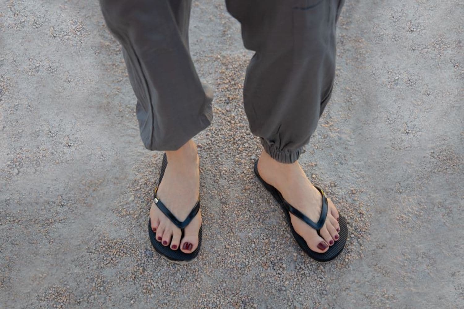 Close up of woman with feet on dirt /gravel wearing Harmony 783 black conductive earthing plug flip flops
