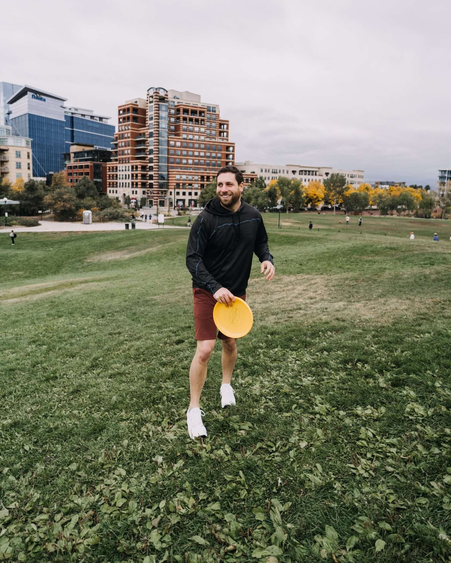 Man wearing shorts and white bamboo grounding sneakers for earthing on grass playing frisbee