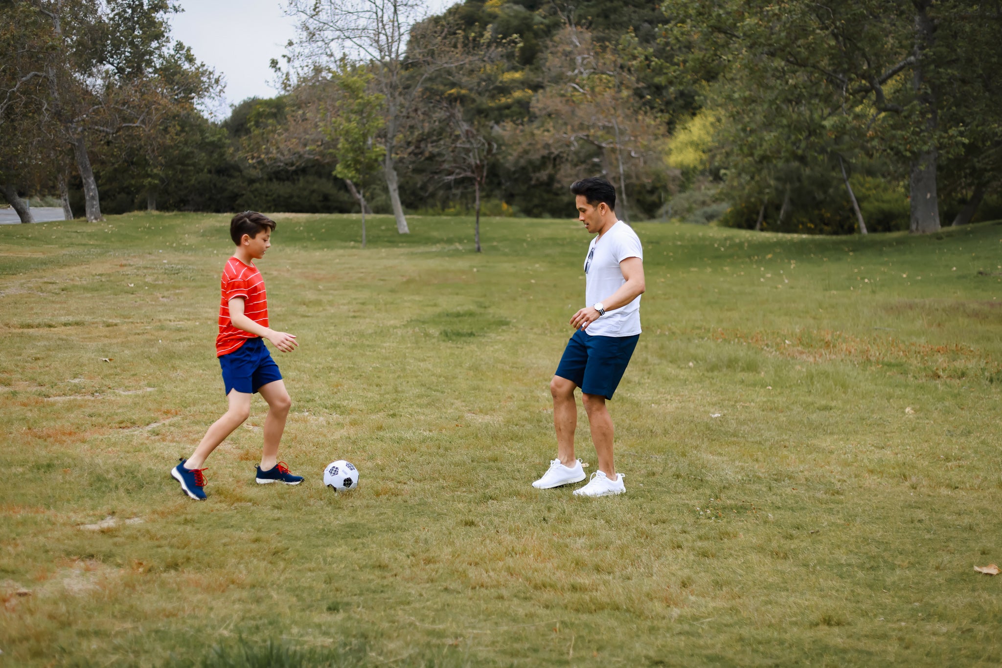 Father and son playing soccer in field while grounding in Harmony 783 grounding sneakers.