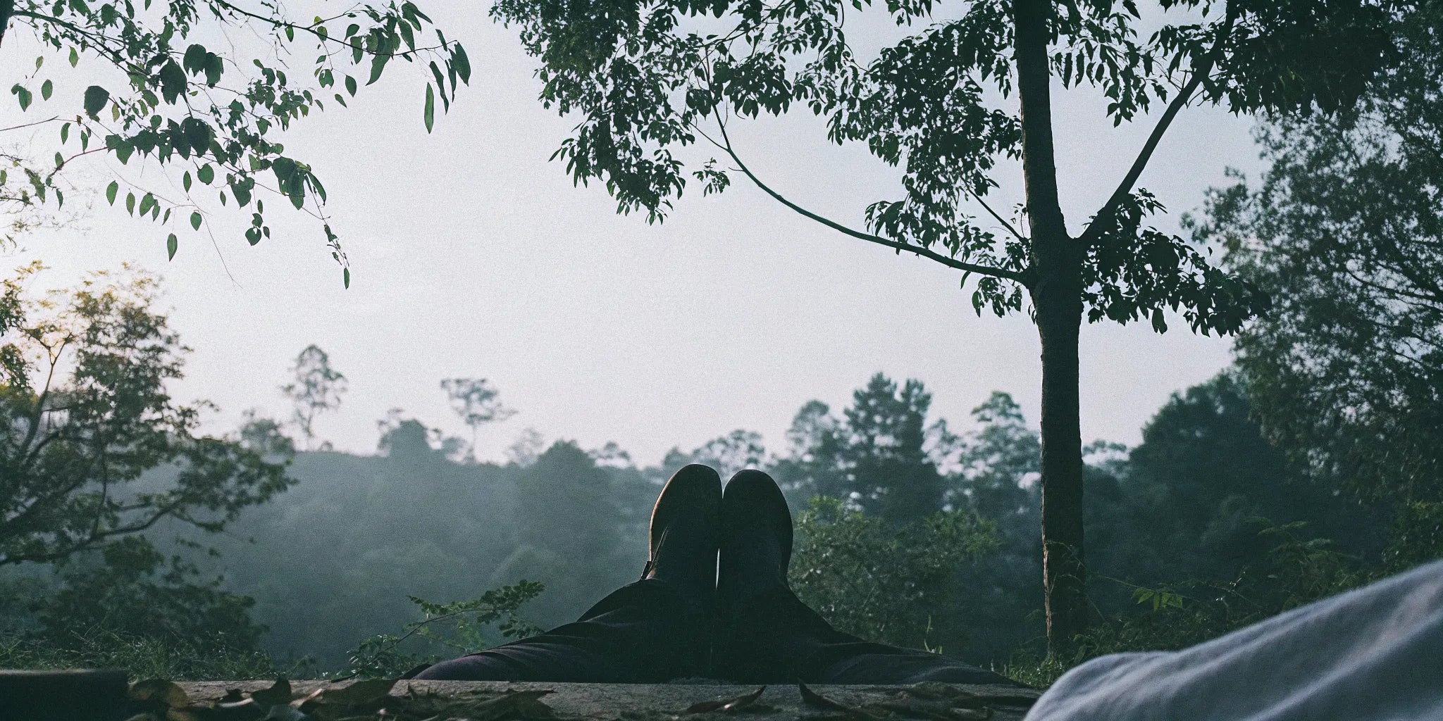 A serene, peaceful outdoor setting of a person meditating with feet resting on the natural earth in warm morning light