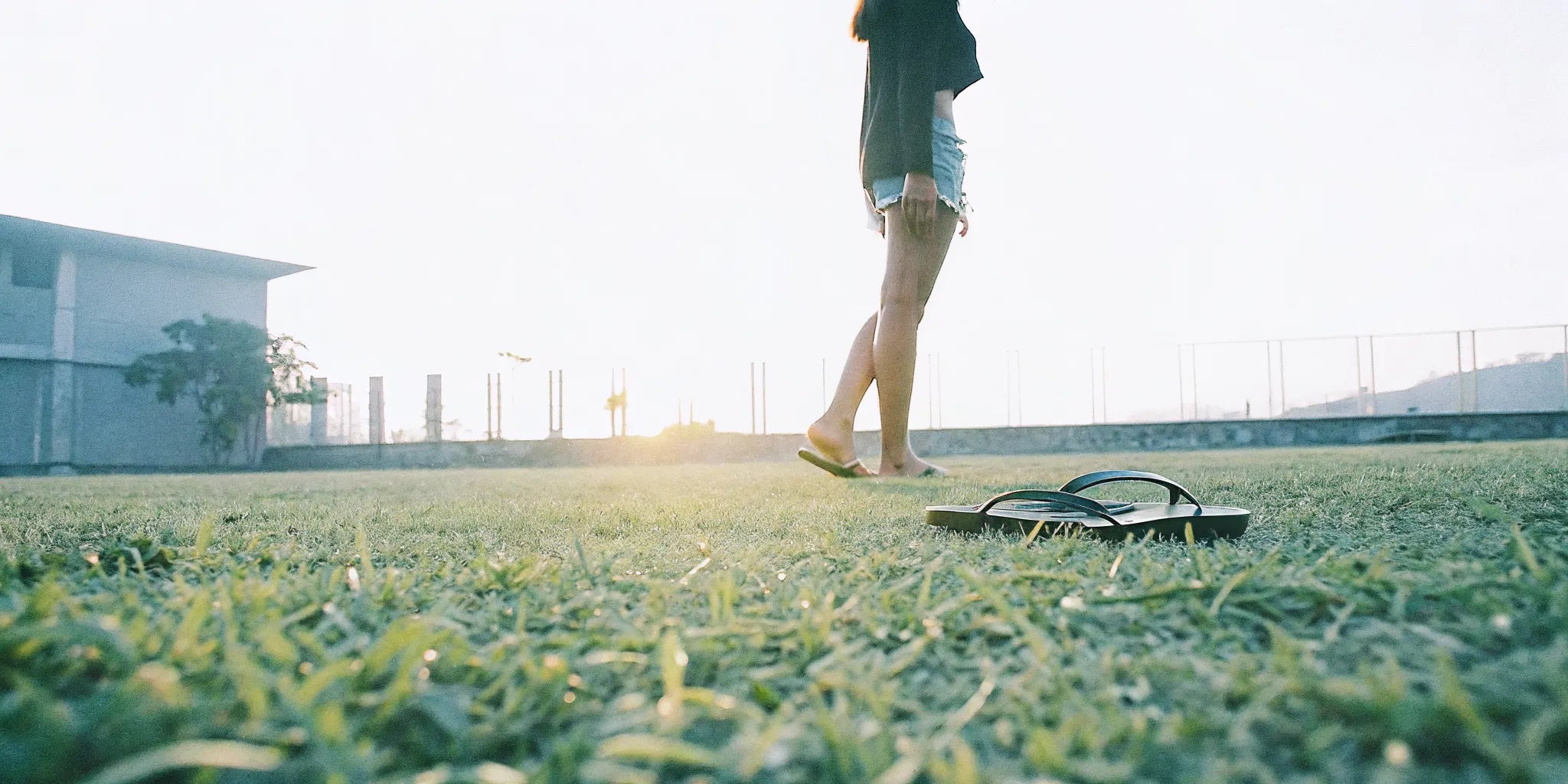 Grounding sandals and flip flops on grass beside bare feet