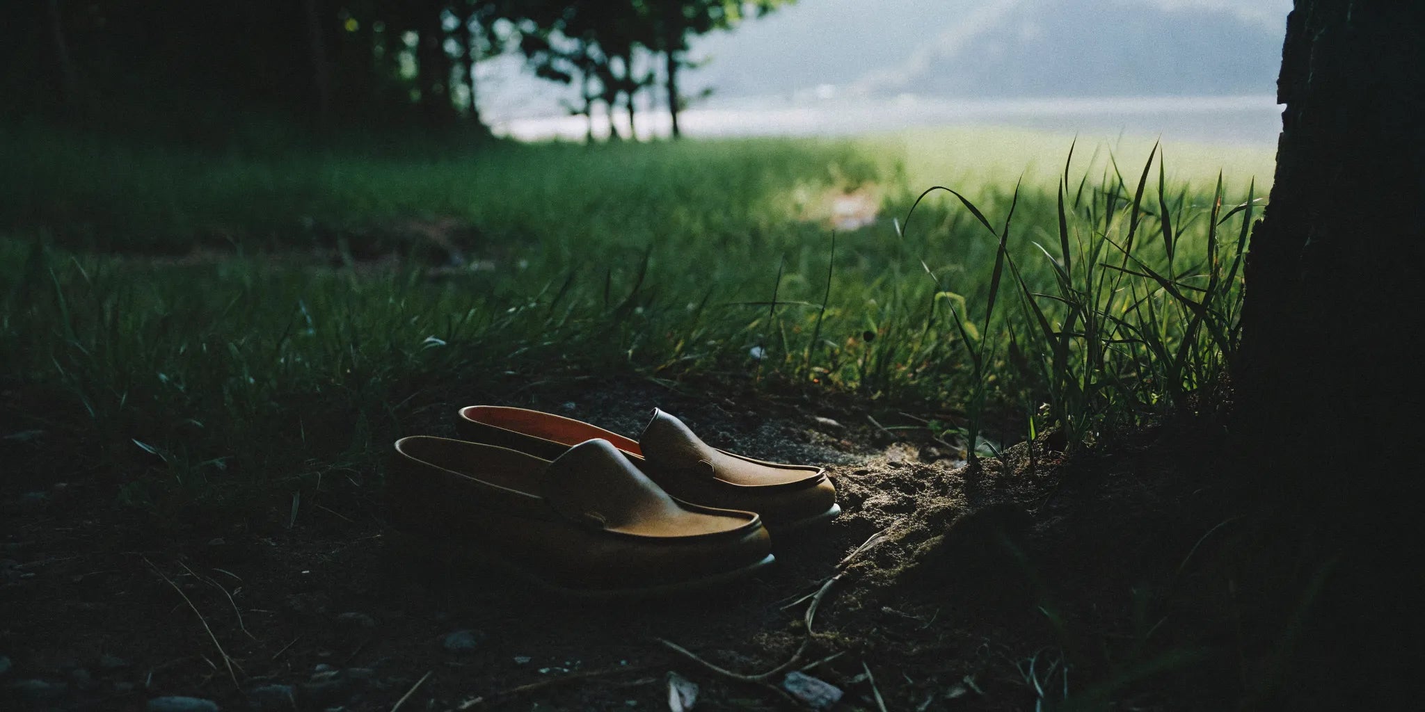 Tan grounding shoes resting on natural earth beside grass