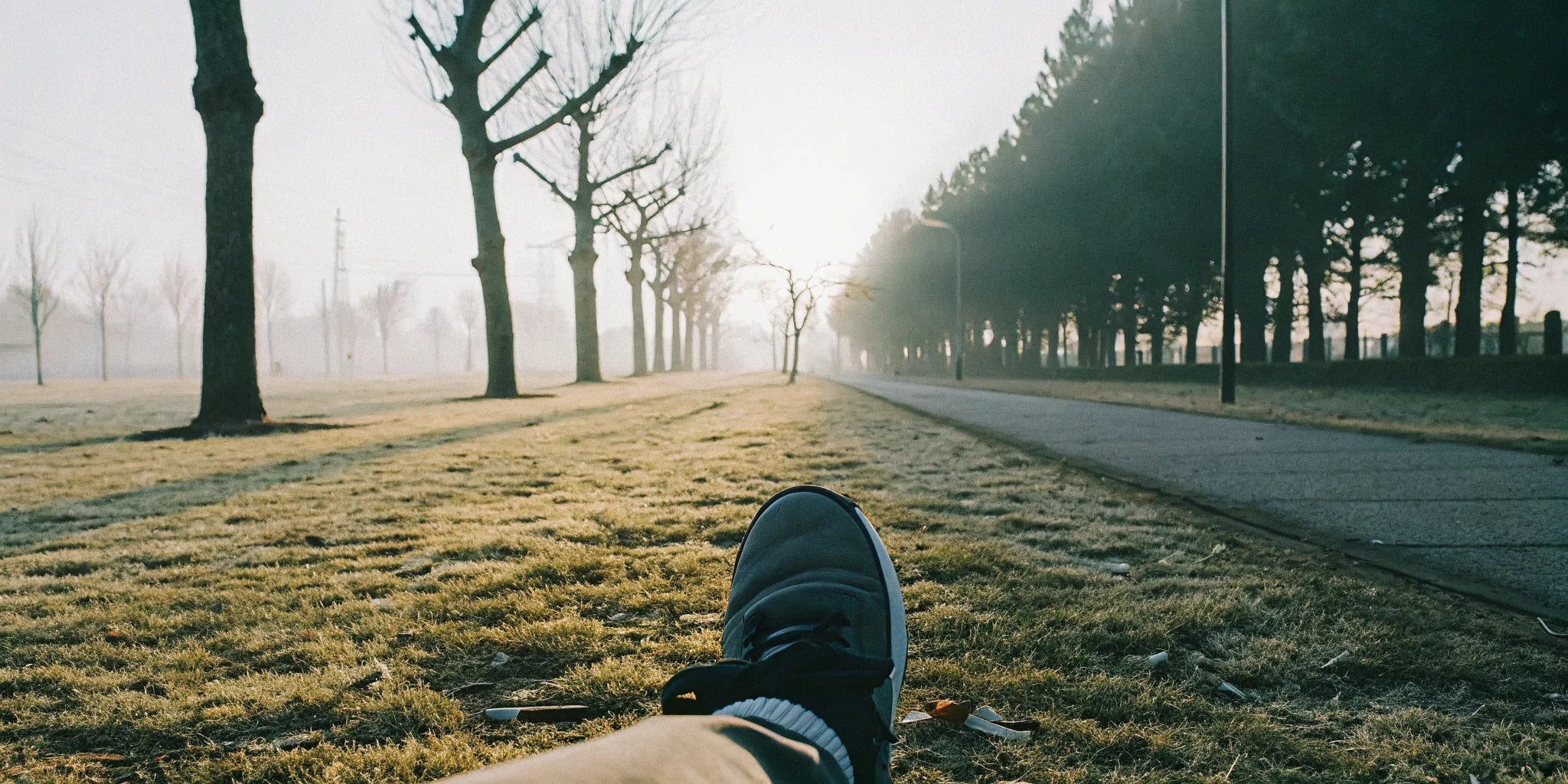 Person wearing grounding shoes walking on a grassy park path