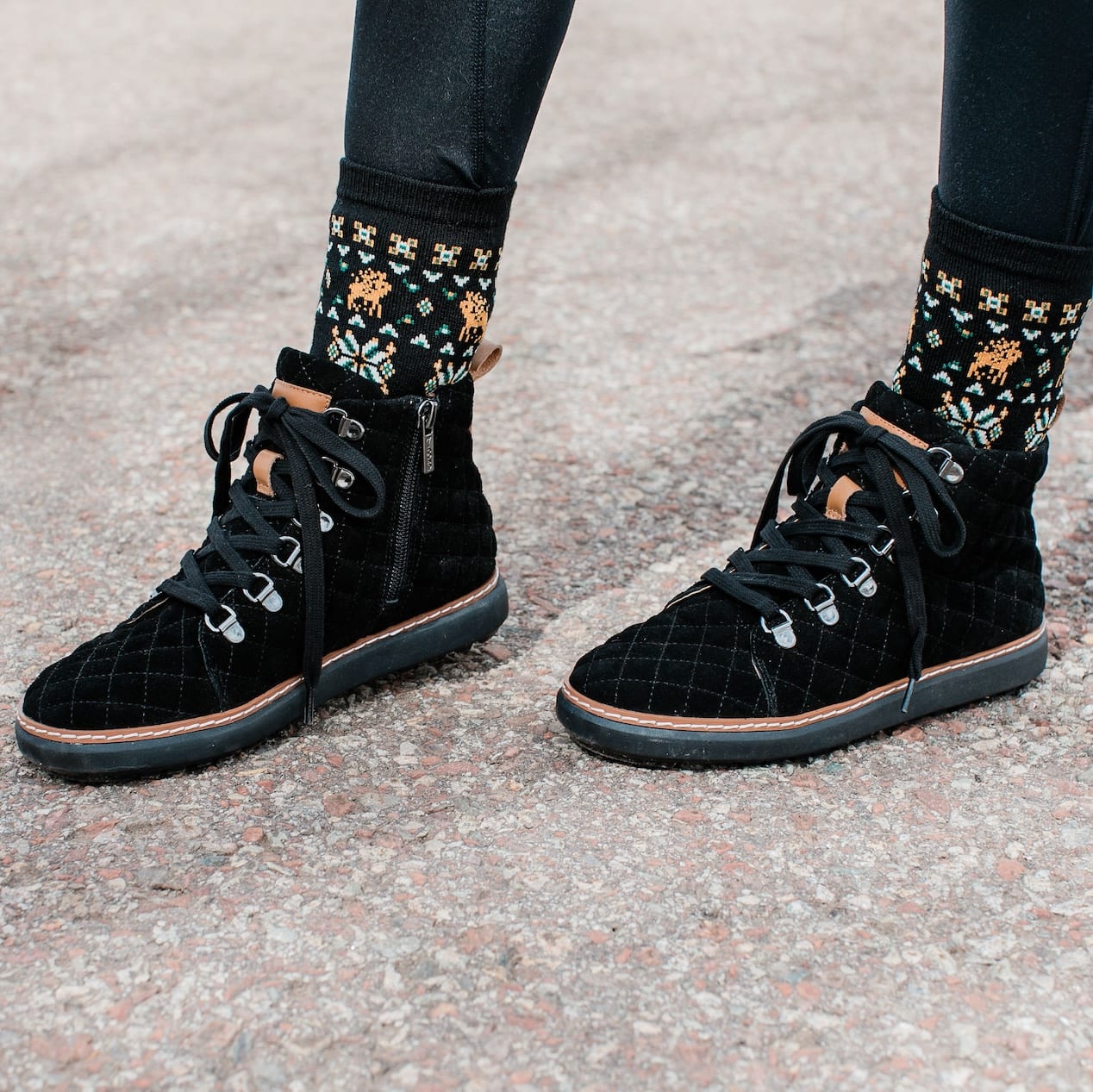 Woman wearing festive wool grounding crew socks in black quilted grounding high-top boots