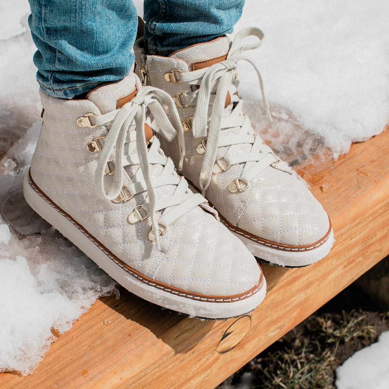 Woman wearing gold quilted sparkly grounding high-tops in snow