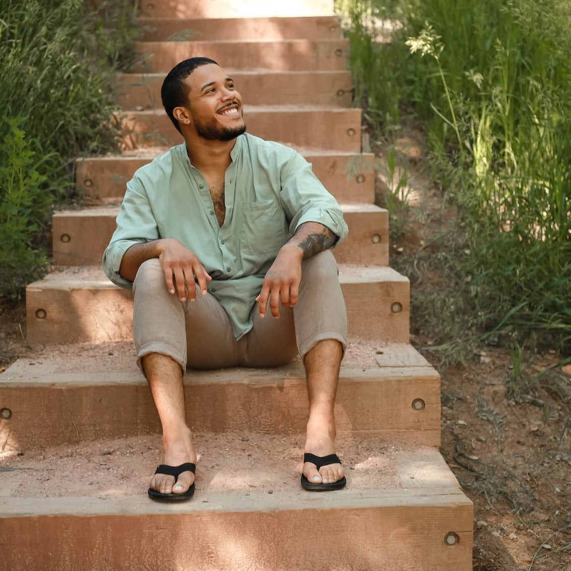 Close up of man sitting on steps wearing Harmony 783  tatum black knit sandal conductive
footbed earthing 