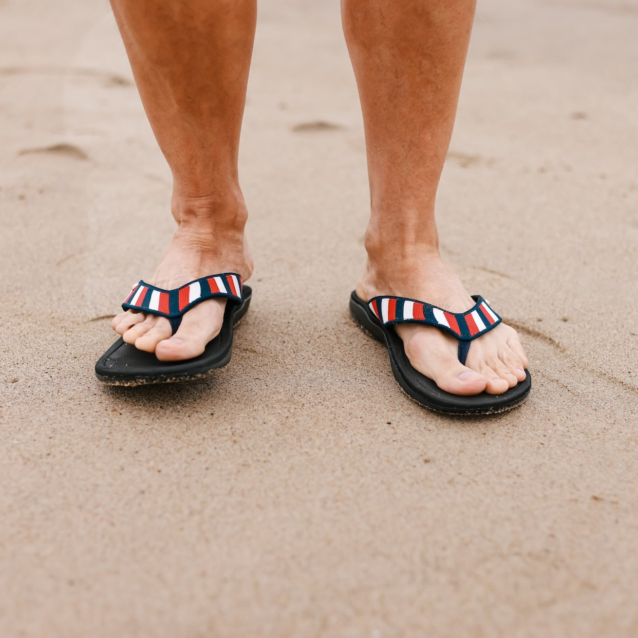 Close up of man standing on sand at the beach wearing Harmony 783 red white and blue striped knit conductive
footbed earthing 