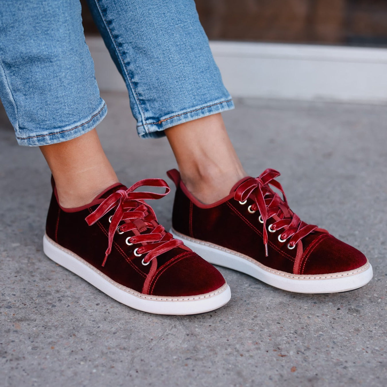 woman standing on unfinished concrete wearing bordeaux red velvet grounding walkers with velvet laces