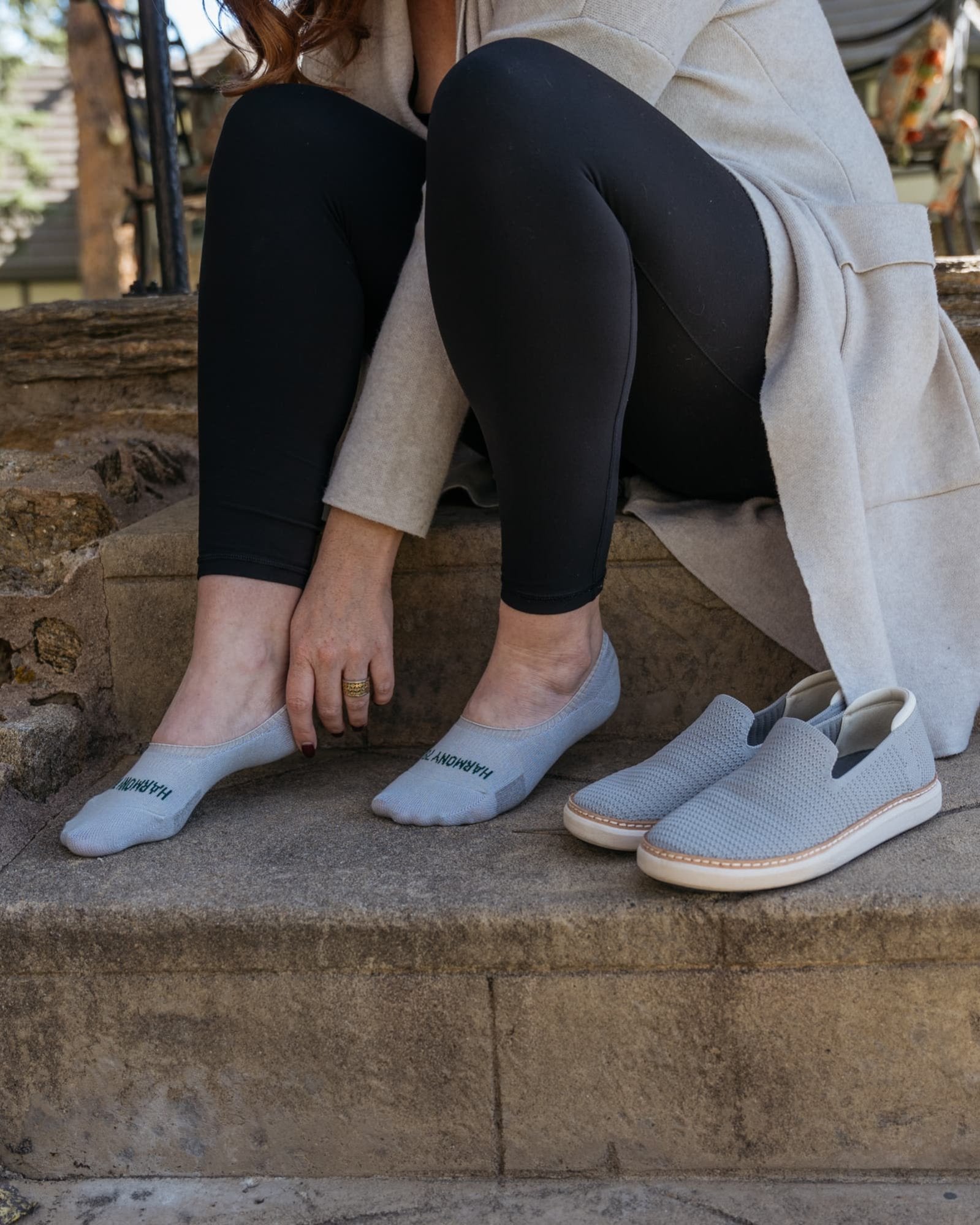 Close up of sitting on stone steps putting on Harmony 783 No Show Grey Grounding earthing socks Organic Cotton