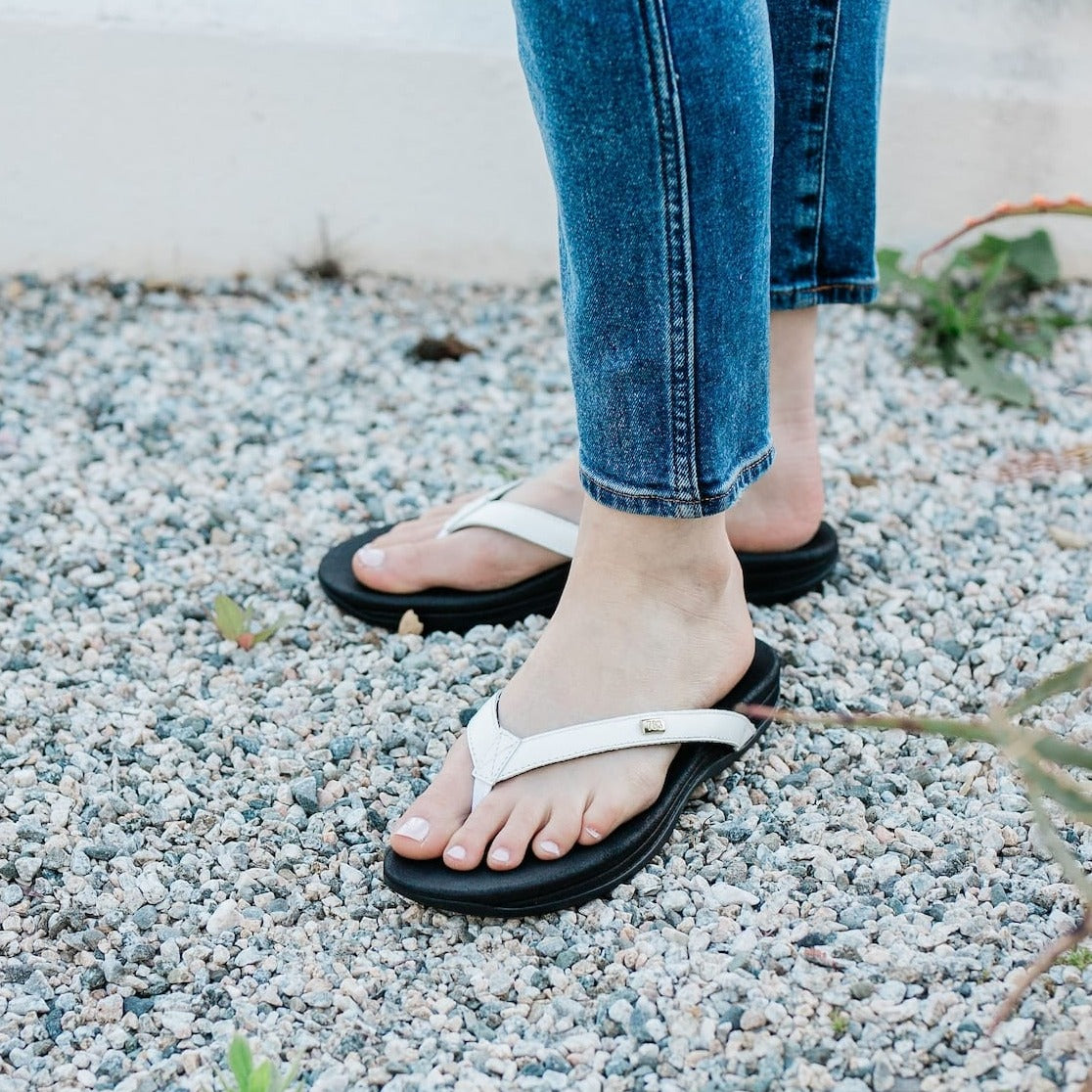  Close up Woman  in blue jeans standing on gravel and rocks wearing Harmony 783 Women’s Lily White leather Grounding Conductive Earthing Sandal Flip Flop 
LIfestyle1