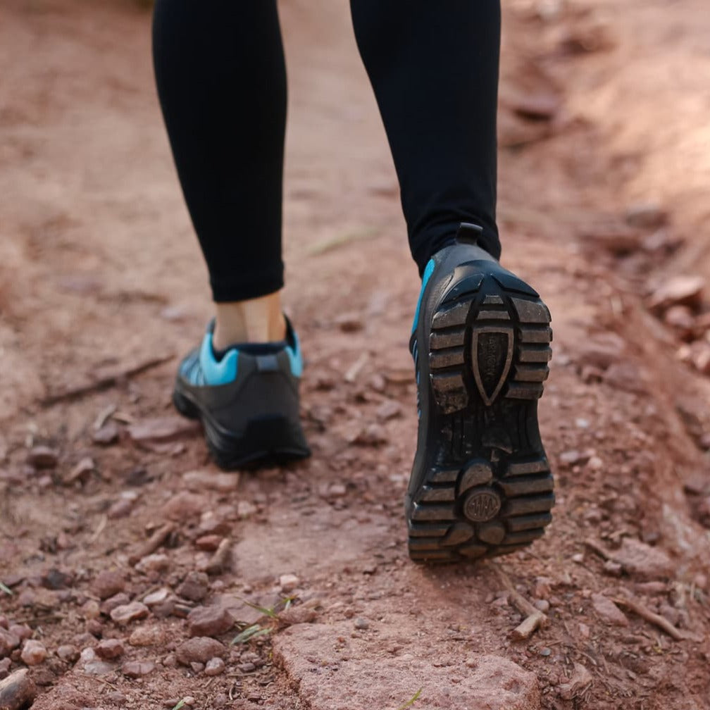 Woman walking wearing the Blue and Grey Grounding Trail shoe showing the tread on the bottom of the earthing shoe