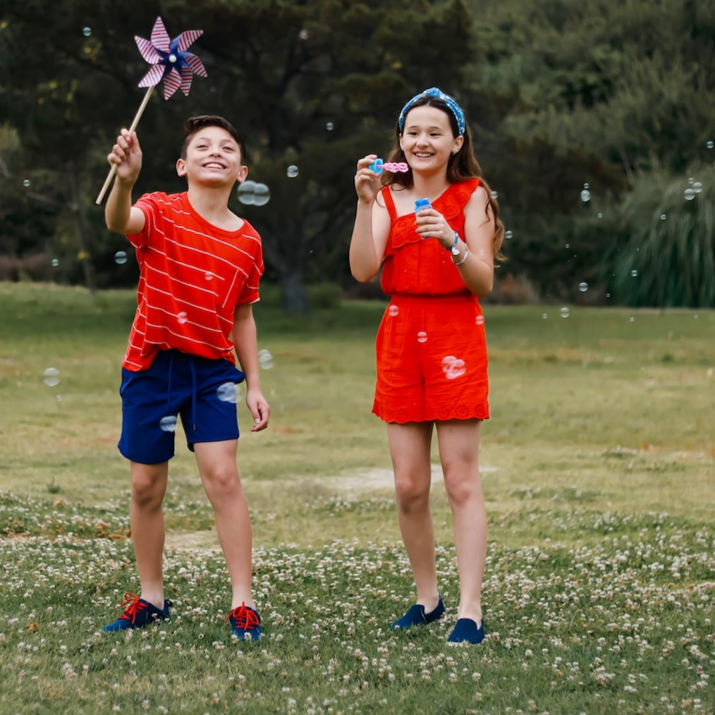 Kids wearing navy bamboo slip-on and sneaker grounding shoes in grass