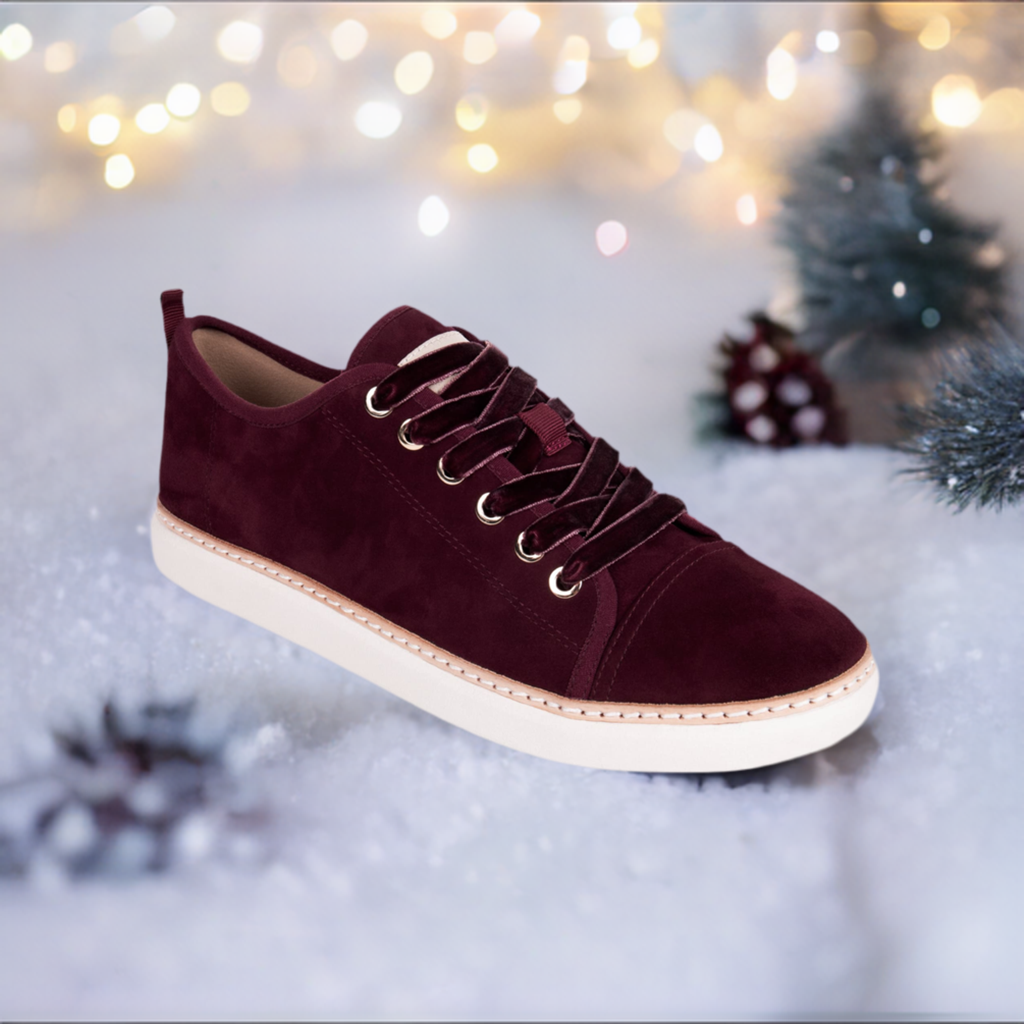 Cabernet suede grounding walker sitting on snow with trees, pinecones, lights in background