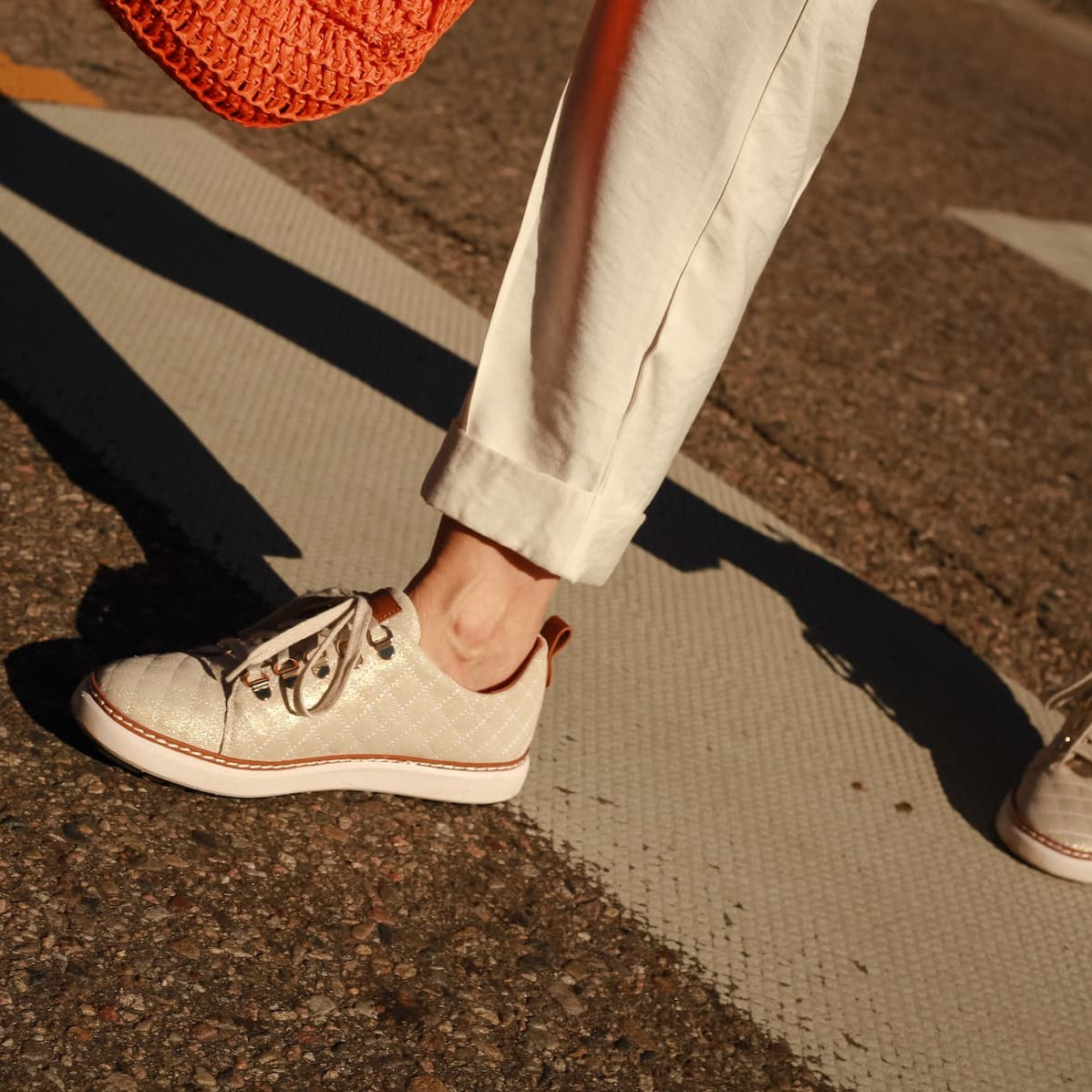 Woman walking wearing Melissa gold creme quilted sparkly walking shoes for grounding and earthing