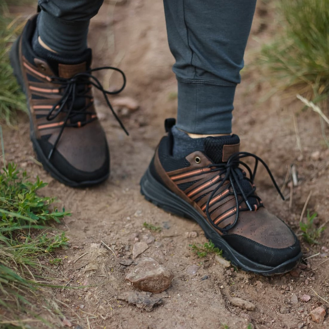 Man walking on trail wearing joggers and brown leather and black mesh grounding trail shoes for earthing