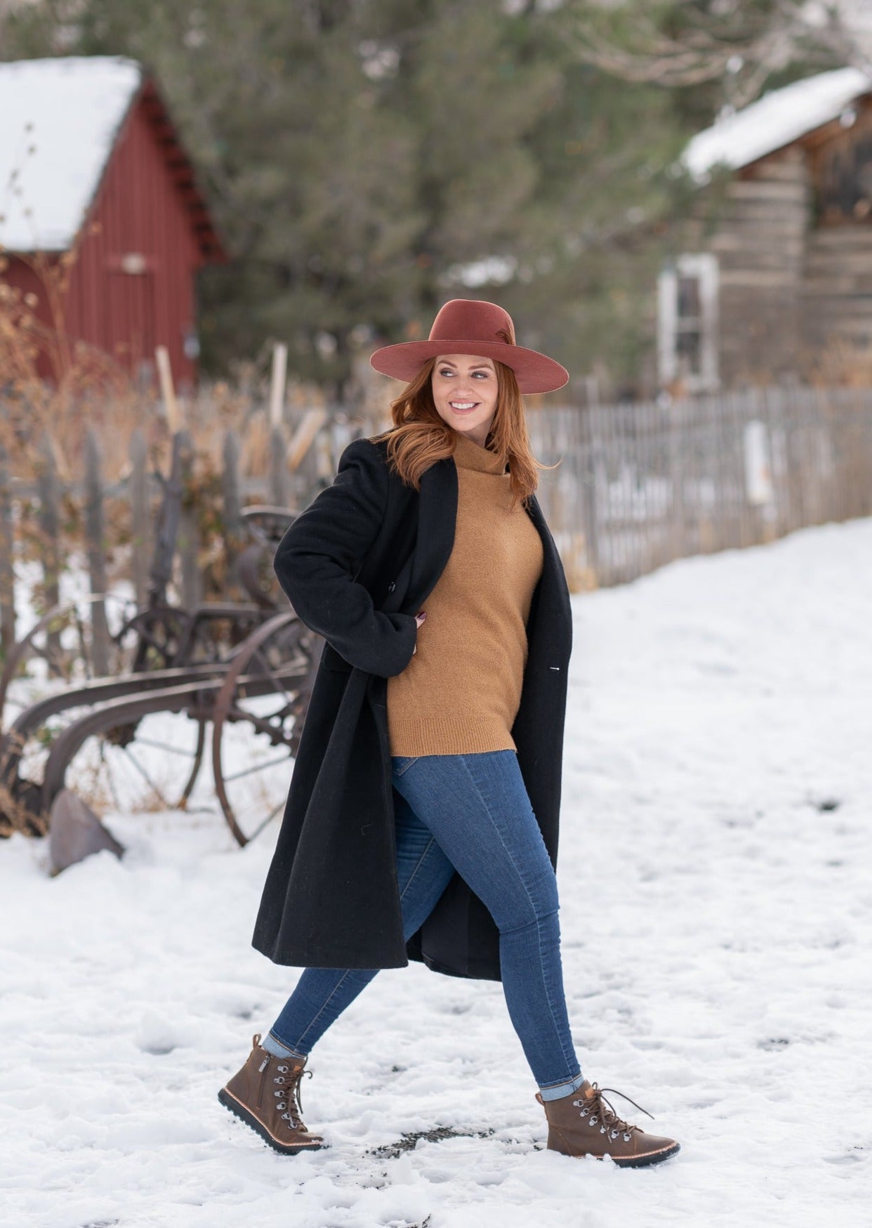 Woman walking in snow wearing jeans and high-top brown leather grounding boots