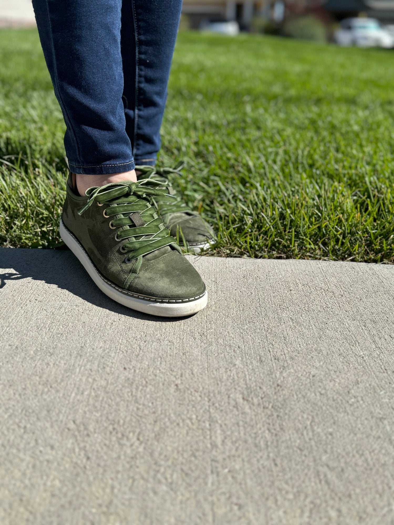 Woman walking from grass to concrete wearing Charlotte Olive Green Suede grounded walkers