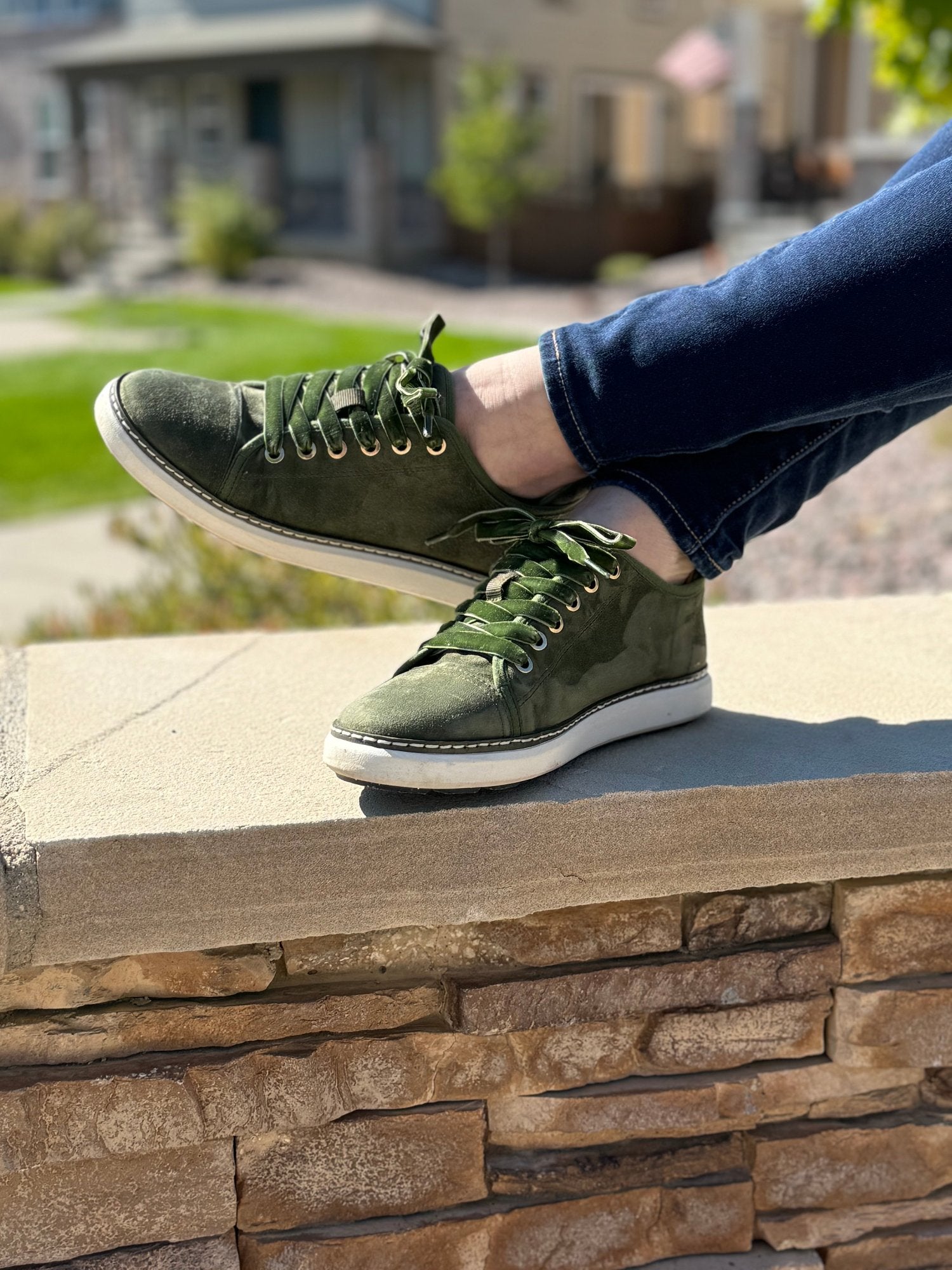 woman's crossed legs on stone wall wearing charlotte olive green suede grounding walker