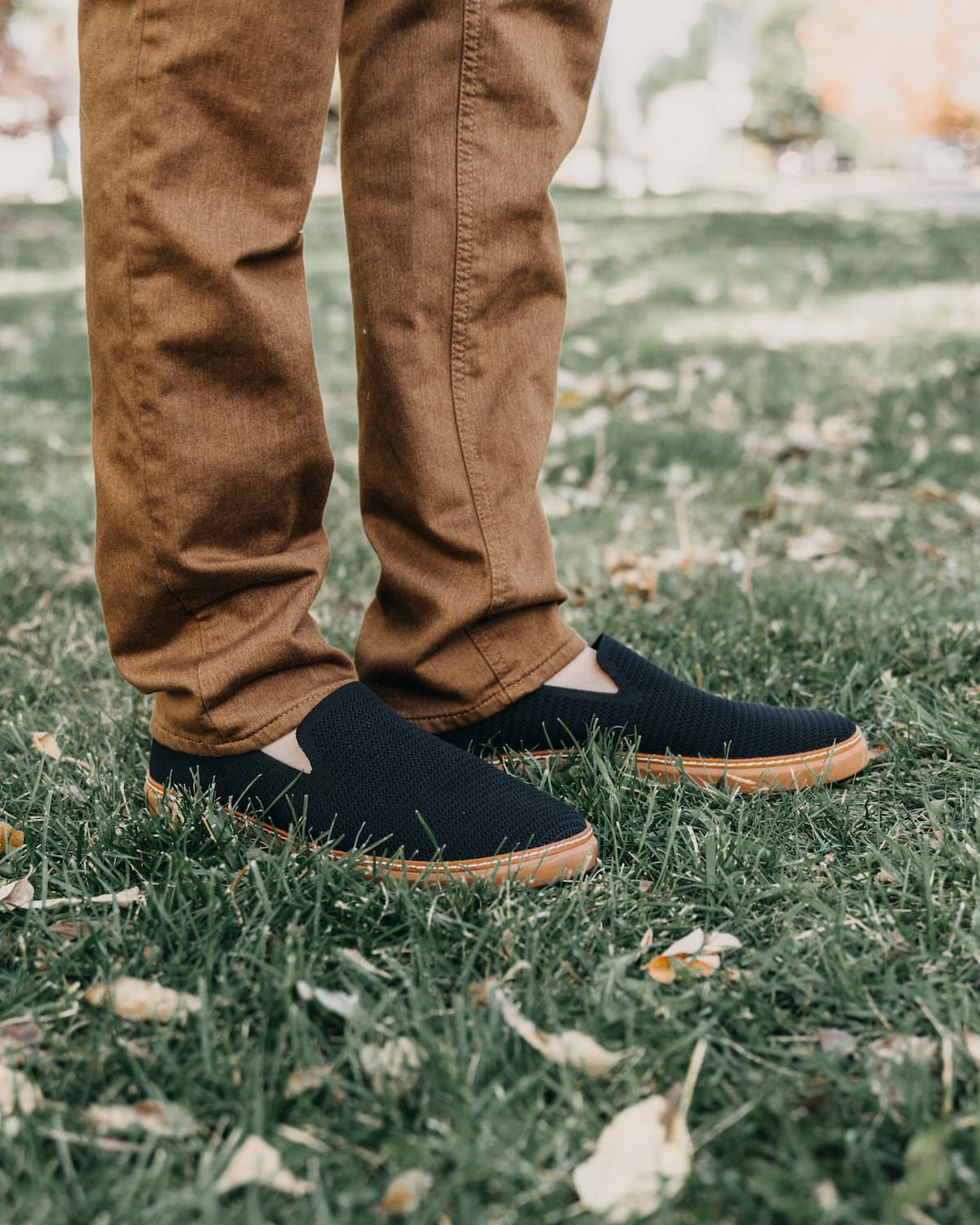 Man wearing bamboo slip-ons black and cognac in grass with long pants in fall