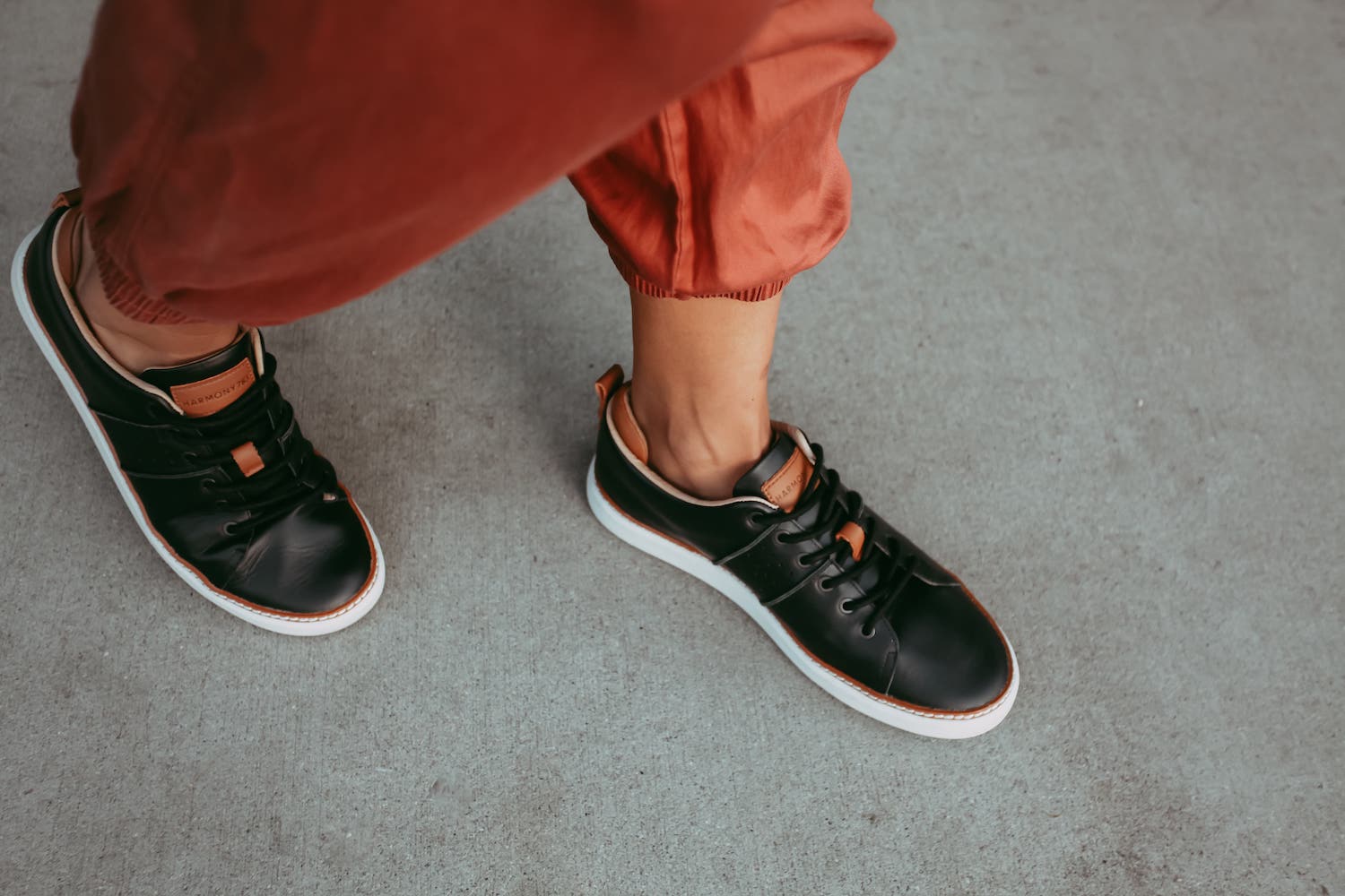 Woman wearing black leather grounding shoes on concrete with orange pants