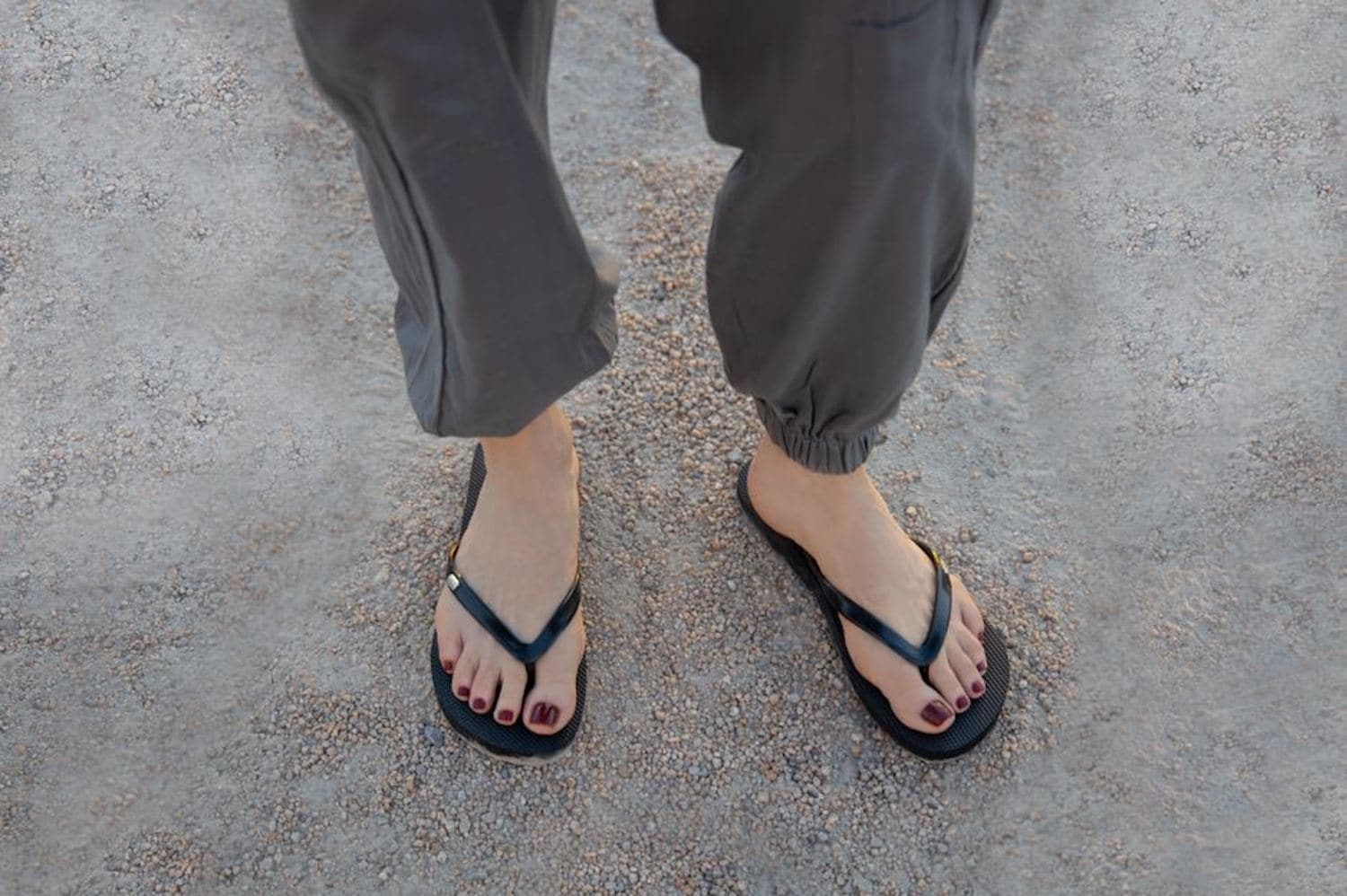 Close up of woman with feet on dirt /gravel wearing Harmony 783 black  conductive earthing plug flip flops