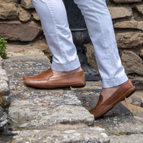 man walking up stone steps wearing brown leather grounding driver