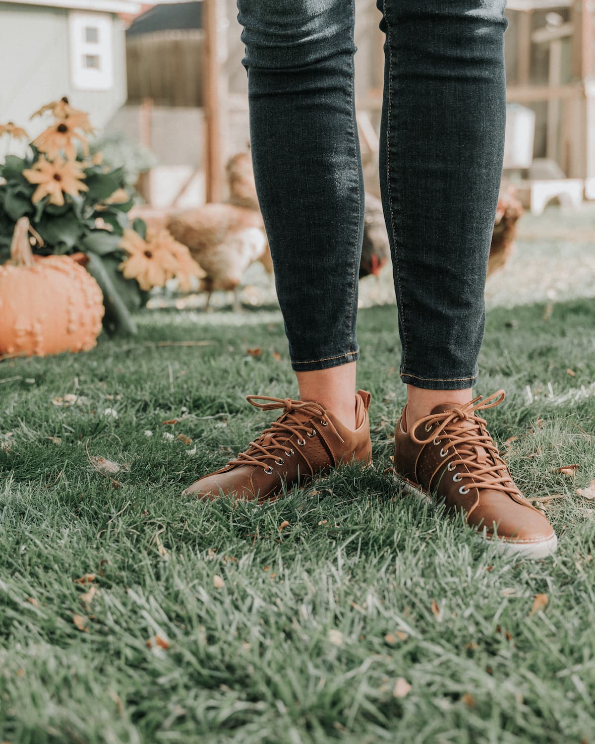 Woman wearing brown leather grounding walking shoes with grey soles in grass