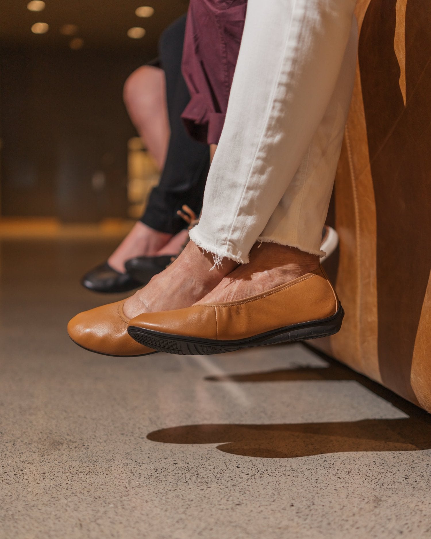 Woman wearing white jeans and cognac leather ballet flats